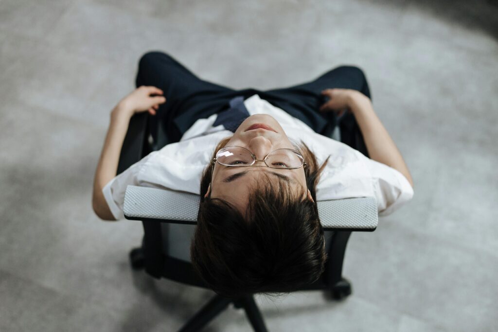 Man in white shirt and glasses reclining in chair, viewed from above.